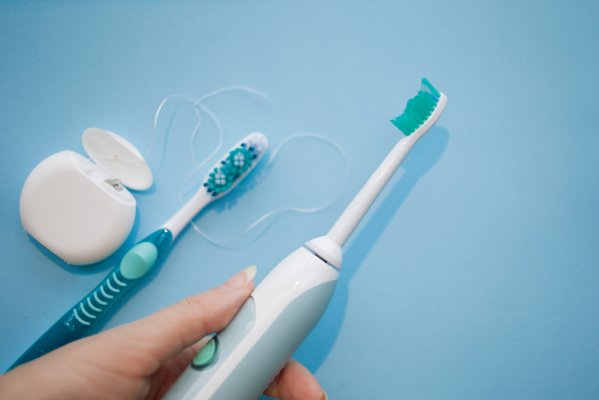electric toothbrush beside a manual toothbrush